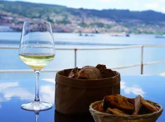 : Glass of Albariño white wine with bread and Atlantic coastal views on a Rías Baixas day trip from Santiago de Compostela