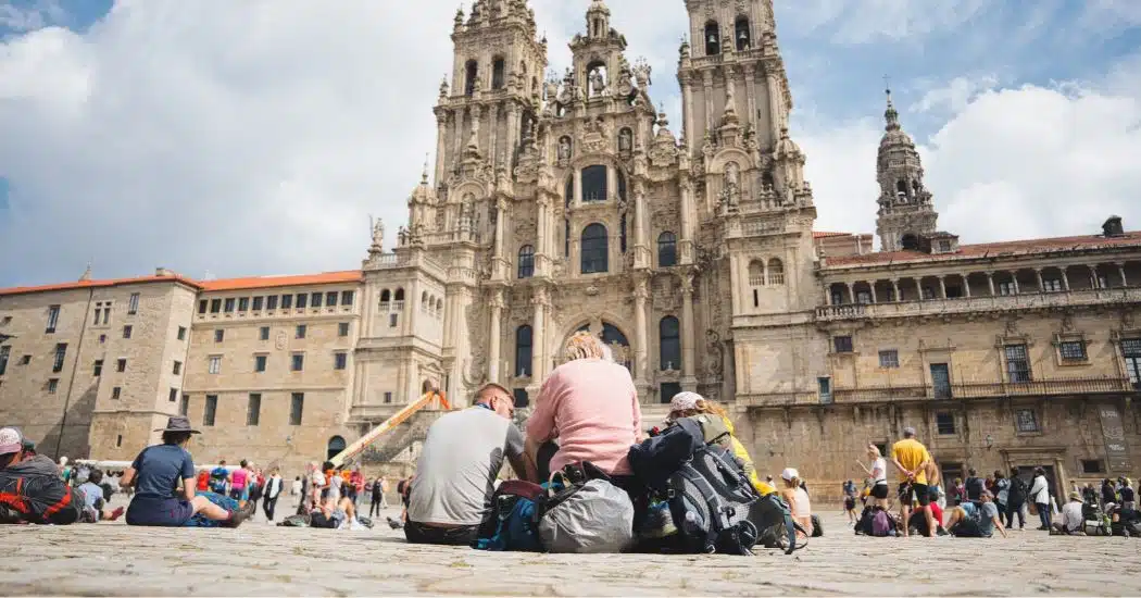 Two pilgrims seen from behind, looking up at Santiago de Compostela Cathedral at the end of their Camino